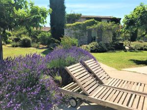 ゴルドにあるMas Oréa côté piscineの紫の花の庭園内の木製ベンチ