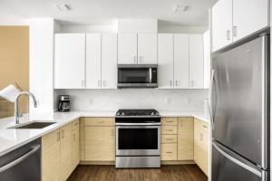 a kitchen with white cabinets and a stainless steel refrigerator at Newton 1BR w WD nr Newtonville Train BOS-737 in Newton