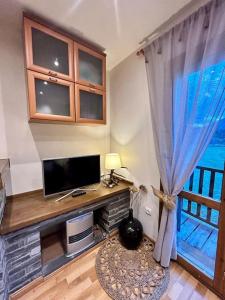 uma sala de estar com televisão e janela em L'allotjament rústic d'Ainet em Vall de Cardos
