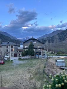 una casa en un campo con montañas en el fondo en L'allotjament rústic d'Ainet, en Vall de Cardós