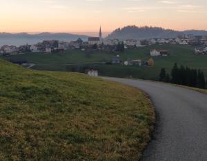 a winding road on a hill with a town in the distance at Ferienwohnung in Schwellbrunn in Schwellbrunn