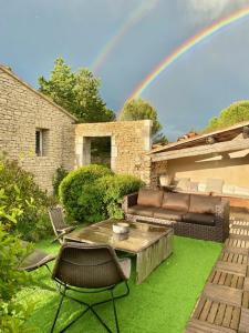 un patio con sofá, mesa y arco iris en Mas OREA, en Gordes