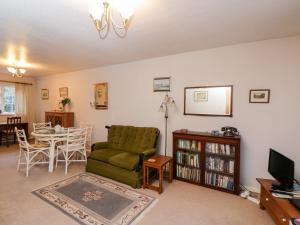 a living room with a green couch and a table at Poets Corner in Great Malvern