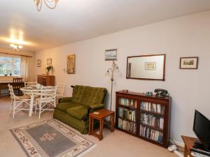 a living room with a green couch and a table at Poets Corner in Great Malvern