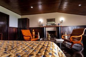 ein Schlafzimmer mit 2 Stühlen, einem Bett und einem Kamin in der Unterkunft Hotel Highlander in Gravatá