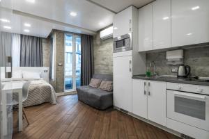 Luxury Studio Silver by Flat Mаnager في صوفيا: مطبخ مع دواليب بيضاء وسرير في الغرفة