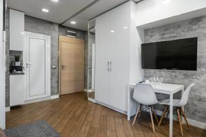 Luxury Studio Silver by Flat Mаnager في صوفيا: غرفة معيشة مع طاولة وكراسي وتلفزيون