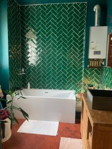 uma casa de banho com uma banheira e uma parede em azulejo verde em Charmante chambre double chez l'habitant em Pantin