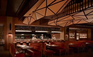 uma sala de jantar com mesas e cadeiras e pessoas na cozinha em Nobu Hotel Atlanta em Atlanta