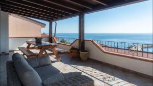 a patio with a couch and a table on a balcony at Cala Gonone house in Cala Gonone