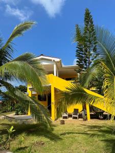 a yellow house with palm trees in front of it at Sunshine Hotel Little Corn Island in Little Corn Island