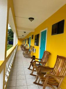 una fila de mecedoras sentadas en un balcón en Sunshine Hotel Little Corn Island en Little Corn Island