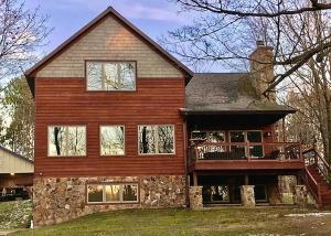 Cette grande maison en bois dispose d'une terrasse couverte et d'un balcon. dans l'établissement Ravensong Lodge, à New Auburn