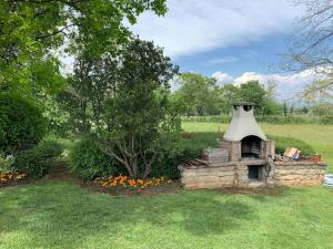 a brick oven in a field with a tree at Villa Paradiso nel verde in Ponte San Marco