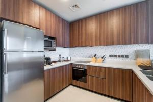 ドバイにあるStunning Views & Palm Marina Views & 39th floorのキッチン(木製キャビネット、ステンレス製の冷蔵庫付)