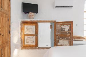 1 dormitorio con TV en la pared y ventana en La Fonda Antigua ADULTS ONLY, en Vejer de la Frontera
