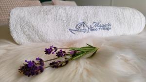 ręcznik z fioletowymi kwiatami na białym kocu w obiekcie Masuria Resort Village, całoroczne domki z widokiem na jezioro, sauna i jacuzzi w mieście Żywki