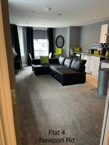 ein Wohnzimmer mit einem schwarzen Sofa und einer Küche in der Unterkunft Stafford apartments in Stafford