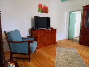 a living room with a tv and a chair at Idill Cottage Vendégház in Tiszafüred