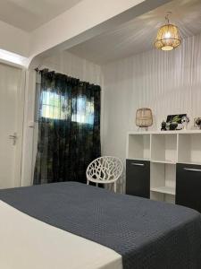 ein Schlafzimmer mit einem Bett, einem Stuhl und einem Fenster in der Unterkunft Tilys lodge in Capesterre-Belle-Eau