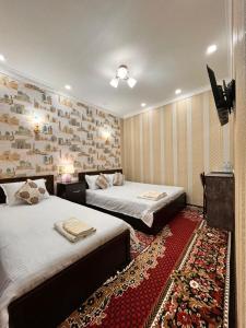 Cette chambre comprend deux lits et une télévision. dans l'établissement Hamida, à Samarcande