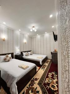 una camera d'albergo con due letti e una televisione di Hamida a Samarkand