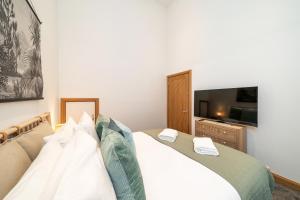 Schlafzimmer mit einem weißen Bett und einem Flachbild-TV in der Unterkunft The Church Front in Montrose