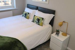 una camera da letto con letto, lenzuola e cuscini bianchi di Welcoming 2 Bedroom Home with Driveway Parking a Morecambe