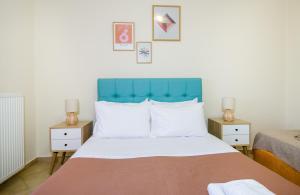 a bedroom with a bed with a blue headboard and two tables at Dioni Family Apartment in Kalathas