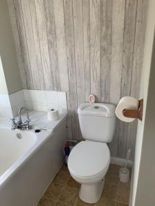 a bathroom with a white toilet and a bath tub at Ratcliffe House - Spacious 3 bedroom House in Sileby in Sileby