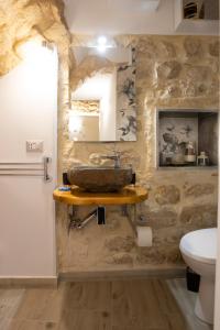 La salle de bains est pourvue d'un lavabo sur un mur en pierre. dans l'établissement L'arco sul fiume, à Scicli