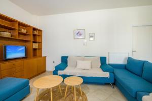 a living room with a blue couch and a tv at Dioni Family Apartment in Kalathas