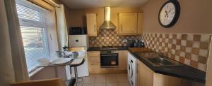 a kitchen with a sink and a clock on the wall at Cosy Stays Daybrook in Nottingham