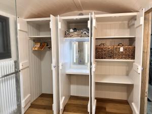 a walk in closet with white shelves and a basket at Cattlestone Farm in West Chiltington