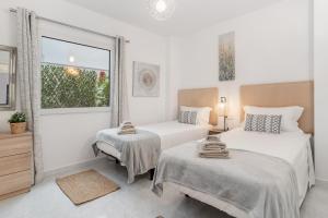 a white room with two beds and a window at Apartamento mediterráneo en el alma de Moraira in Moraira