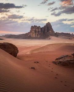 a desert with a large rock formation in the distance at Wadi Rum nature in Wadi Rum