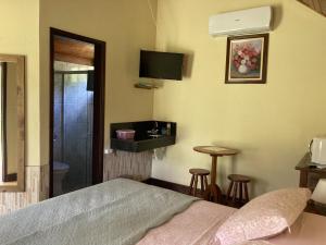 a hotel room with a bed and a bathroom at Pousada Colar de Ouro Chalés in Cunha