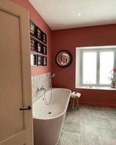 La salle de bains est pourvue d'une baignoire, de murs rouges et d'une fenêtre. dans l'établissement Le Flamand, à Saint-Omer