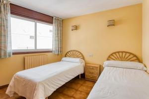twee bedden in een kamer met een raam bij Apartamentos Sanxenxo in Sanxenxo
