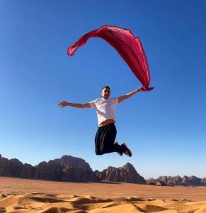 a man is jumping in the desert with a red parachute at Wadi Rum nature in Wadi Rum