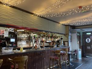 a bar with bar stools and lights on the ceiling at The Ferry Inn in Thurso