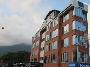 a tall brick building in front of a mountain at Hotel Habitat in Ibagué