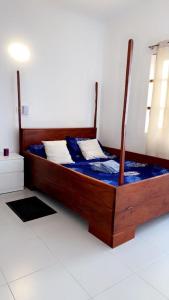 1 dormitorio con cama de madera con sábanas y almohadas azules en Maison individuelle cozy à OUEDO cotonou, 