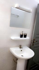 ein Badezimmer mit einem weißen Waschbecken und einem Spiegel in der Unterkunft Maison individuelle cozy à OUEDO cotonou 