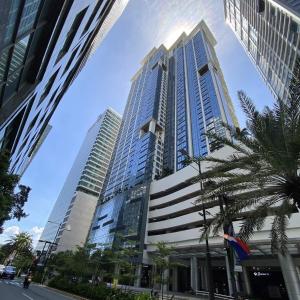 a tall building with a palm tree in front of it at PJ PLACE TO STAY at One Eastwood Tower 1 at Unit 26J in Manila