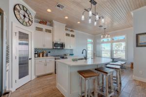 una cocina con armarios blancos y una gran isla con taburetes. en Postcard from Paradise, en Padre Island