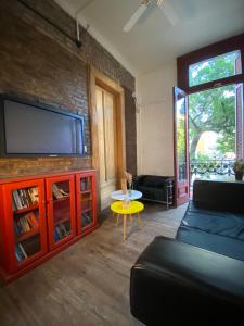 uma sala de estar com uma televisão de ecrã plano numa parede de tijolos em ViaVia BsAs GuestHouse em Buenos Aires