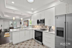 una cucina bianca con armadietti e elettrodomestici bianchi di Walk to UT and E 6th in Fully Equipped ATX House ad Austin