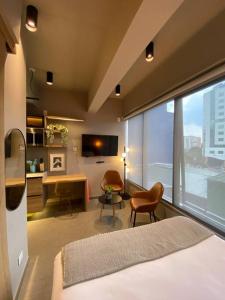 a hotel room with a bed and a desk and a window at Unique loft con piscina cerca a parque 93 in Bogotá