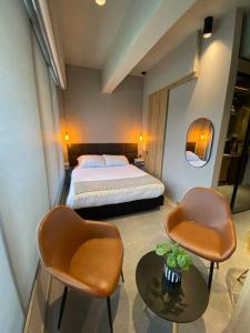 a bedroom with a bed and two chairs and a table at Unique loft con piscina cerca a parque 93 in Bogotá +11 photos